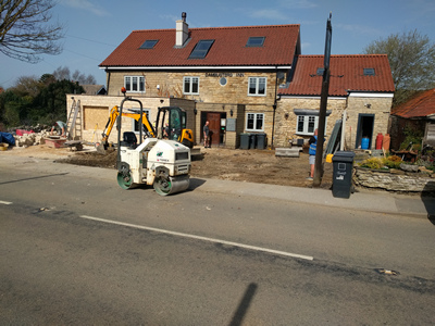 Ext. Day. Pub. The car parking area surface is being compacted in preparationg for resurfacing.