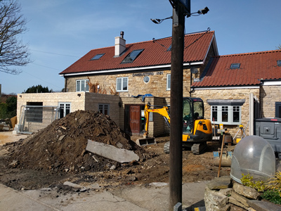 Ext. Day. Pub. Two of the three window openings have had the windows fitted and the car parking area surface is being planed off in preparationg for resurfacing.