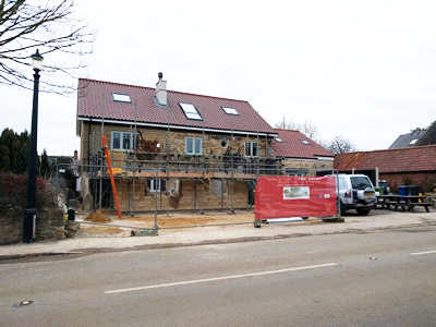 Ext. Day. Pub. Scaffolding erected around the three walls