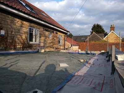 Ext. Day. Pub. The flat roof has been boarded and covered with waterproof membrane.